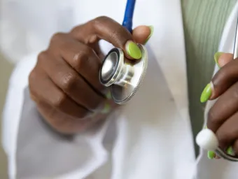 A healthcare student with a clean white lab coat readies their stethoscope