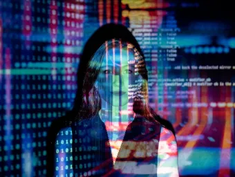 Woman standing with computer screens with code projected on to her.