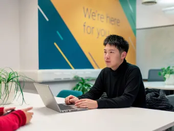 Student using a laptop during a one-to-one careers support conversation in a campus space.