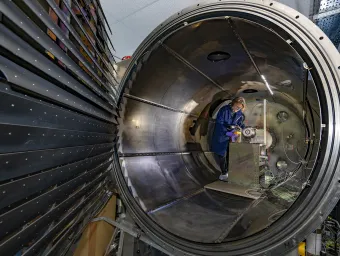 An engineering researcher works on an experiment inside a giant metallic structure.
