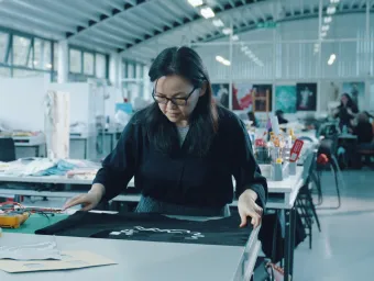 An e-textiles professor examining a smart textile garment with embedded electronics in a Winchester School of Art studio.