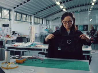 An e-textiles professor examining a smart textile garment with embedded electronics in a Winchester School of Art studio.