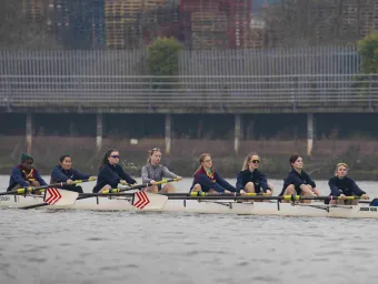 Rowing crew training on a river in an eight-person racing shell with a coxswain.