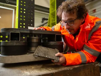 Researcher inspecting specialised vibration testing equipment in a laboratory