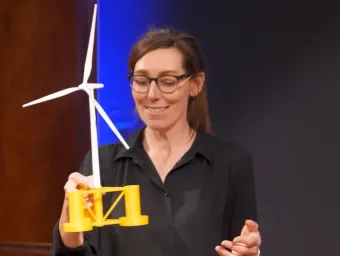 Person holding a model floating offshore wind turbine during a presentation on renewable energy technology