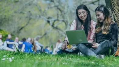 Students using a laptop on the lawn