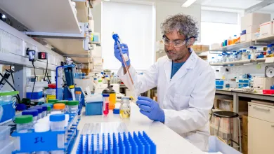 Professor Nullin Divecha working at a lab bench, surrounded by various containers and equipment.