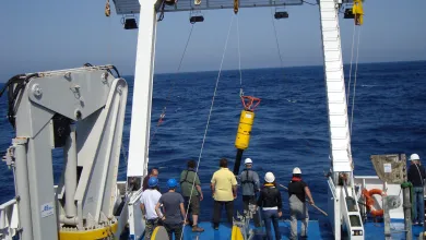 A team onboard a ship lifts an instrument into the water to measure ocean turbulence