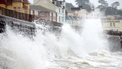Waves crashing on a sea wall opposite houses 