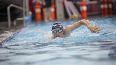 A swimmer in goggles and swimming cap powers towards us in a swimming pool