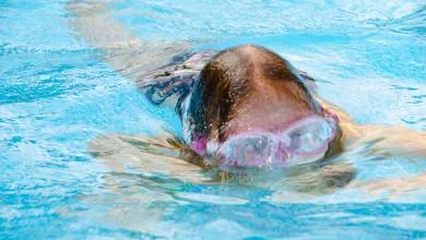 Close up of a child in a swimming pool, their goggles features peeping above the water