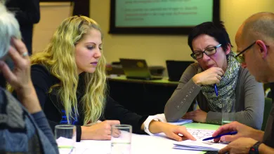 4 people around a table looking at a document