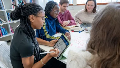 Ria Moses in a group meeting holding an iPad