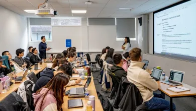 Students sitting at desks while a student is talking to the lecturer