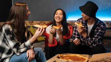 Three teenagers eating takeaway pizza
