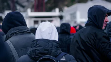 View looking at the backs of people with coats and hoodies on