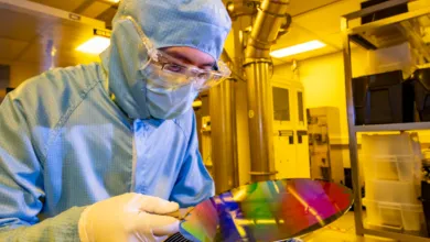 A researcher in a cleanroom suit with a 200mm wafer in the nanofabrication cleanroom