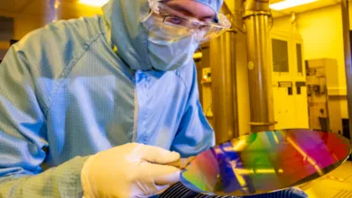 A researcher in a cleanroom suit with a 200mm wafer in the nanofabrication cleanroom