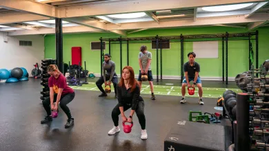 People in a gym lifting a kettlebell from a squatting position
