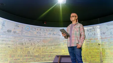 Person stands in front of a 180-degrees curved screen, which is displaying a historic painting