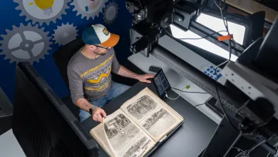 A person is shown using scanning equipment to scan a historic document
