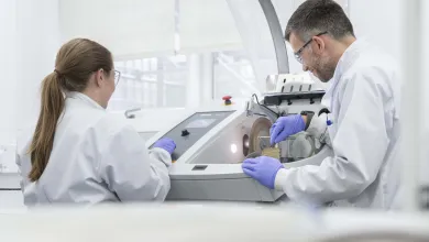 2 researchers placing samples in a scintillation counter.
