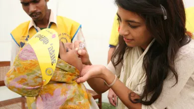 Woman giving a child a polio vaccination