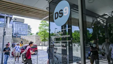 A picture of the Engineering Design Show 9 artwork "DS9" on the glass windows of an engineerin building, there are students walking past in the background.