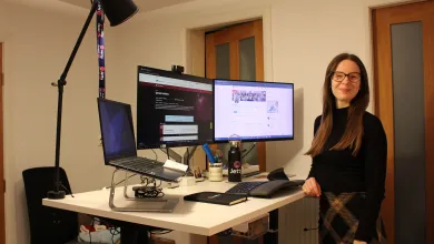 Elizabeth Gardiner standing for a photo next to a dual monitor computer set-up.