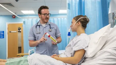 Student nurse helping patient with breathing equipment