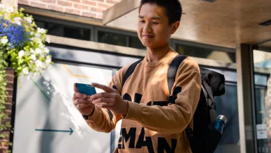 A student holding their ID card while stood outside the entrance to University of Southampton's Student Hub.