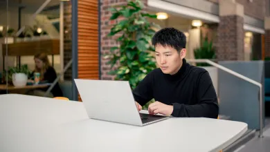 A student sat at a desk in the University of Southampton's Student Hub, with a laptop open on the desk.