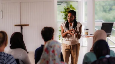 Monique, a Black Futures scholar, presents to an audience at a conference in a bright room.