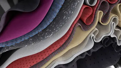 A close-up view of layered, folded fabrics in different colours and textures, shown in a wavy, rippled arrangement.