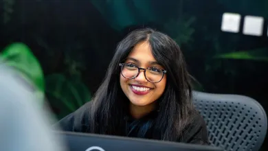 Smiling team member at a desk, ready to help with customer enquiries.