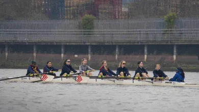 Rowing crew training on a river in an eight-person racing shell with a coxswain.