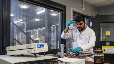 Researcher conducting electrical testing on specialised equipment in a laboratory, with measurement and monitoring instruments in the foreground