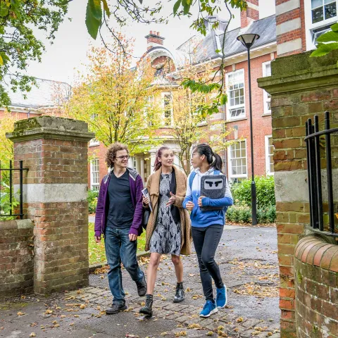 Students walking through gates outside the impressive buildings of Avenue Campus.