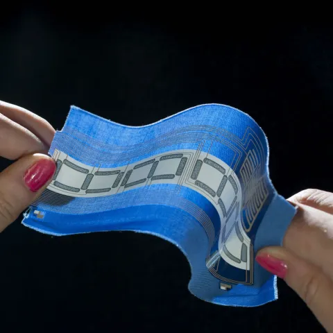 Two hands holding a piece of fabric with embedded circuitry