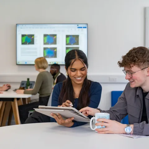 Two students using a tablet in a University study space.