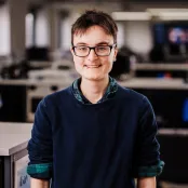 Portrait image of Lucy standing in a lab, smiling at the camera.
