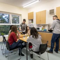 A group of students talking and cooking in a halls kitchen.