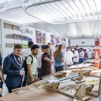 Visitors to the Engineering Design Show look at exhibits on benches. These are prototypes built by students and large printed information boards.