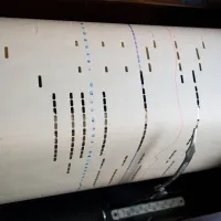 A historical piano roll that uses punched holes on paper and a stylus. 