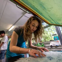 Illustration student works on drawings at a studio table beneath a transparent drawing board.